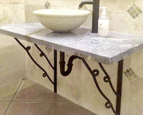 large wrought iron corbels supporting a marble bathroom vanity
