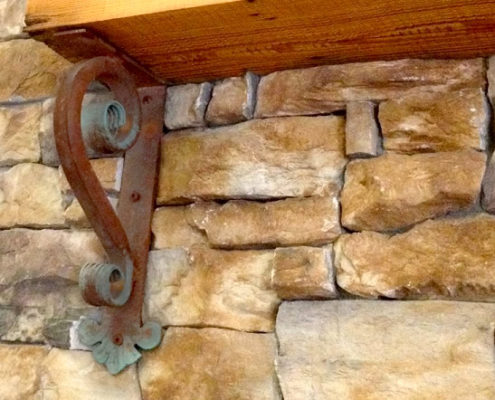 wrought iron corbel with glue patina holding up a wooden mantel